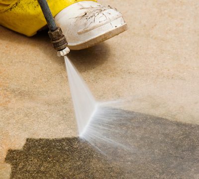 A Greener Property Maintenance professional pressure cleaning concrete.